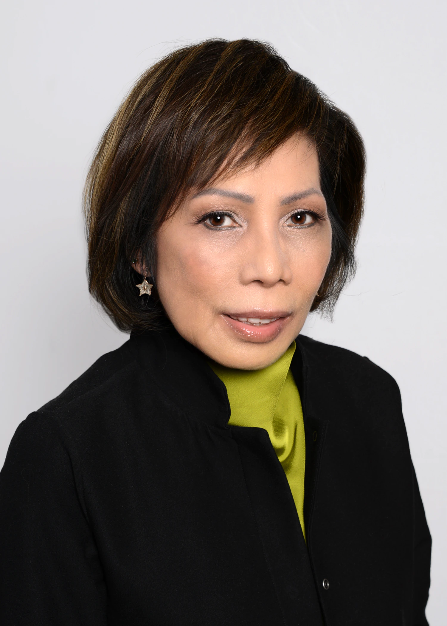 Portrait of a person wearing a black jacket and green top against a plain light background.