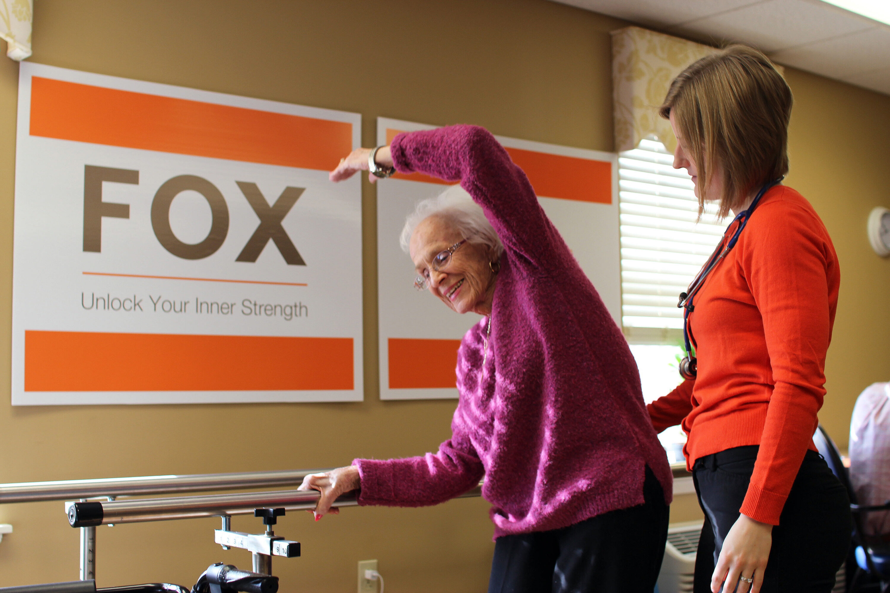 Elderly woman exercising with therapist at rehab center
