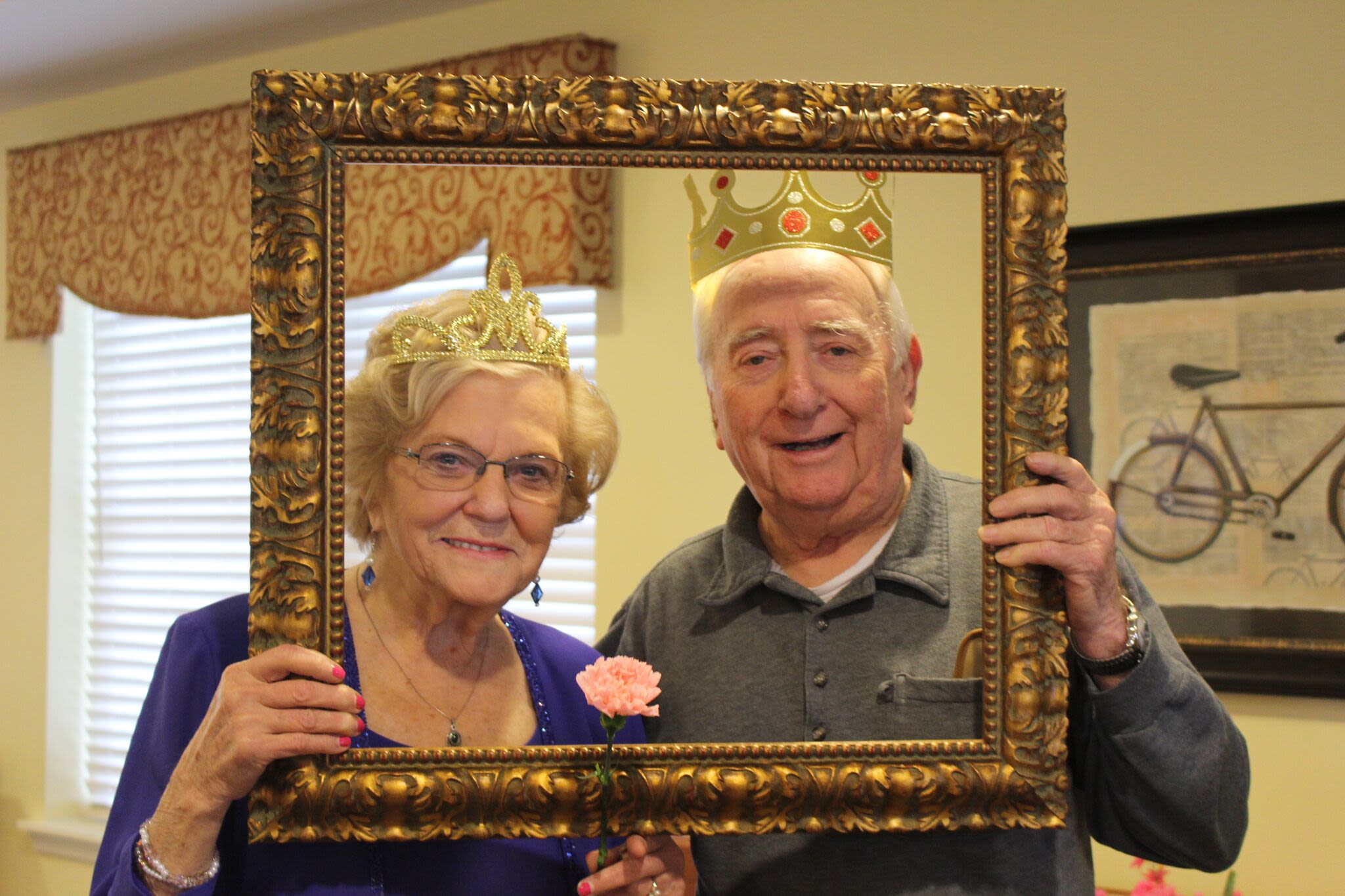 Elderly couple wearing crowns holding ornate frame