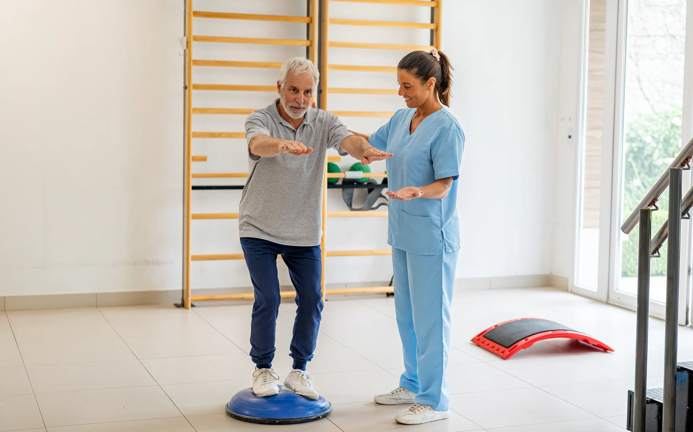 Senior man balancing with physical therapist assistance